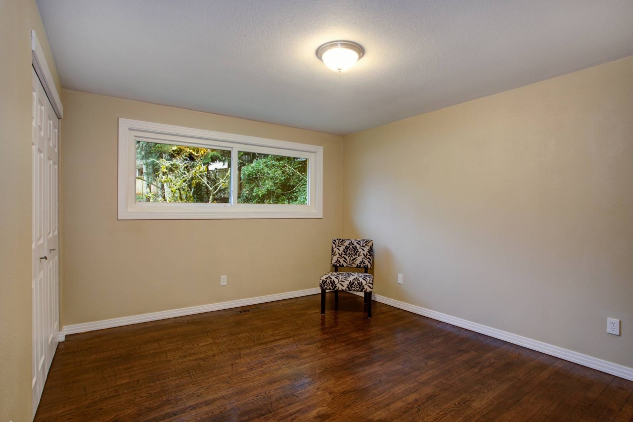 Hopper window in an empty basement room with only a patterned chair in the corner near Peoria, Illinois